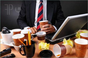Closeup view of a very cluttered businessmans desk. Man is holding a ...