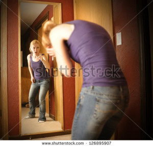young woman is depressed looking in a mirror while the reflection is ...