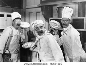Three chefs holding pies for a fight in the kitchen