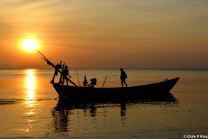 Boys mooring a boat before the sun sets off Rabbit Island, Cambodia ...
