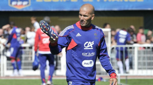 ... player Zinedine Zidane carries football shoes as he leaves the pitch