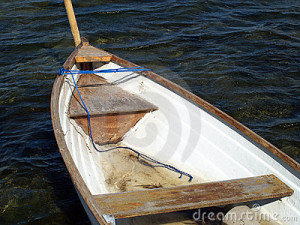 Small classical wooden fishing boat dory rowboat floating on sea water