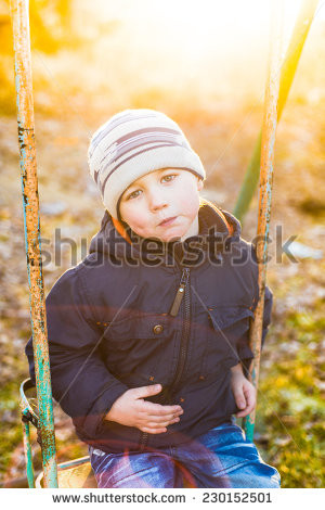 Boy swinging on a swing in a sunny autumn day - stock photo