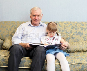 ... 'grandfather and granddaughter sitting on the sofa and reading book