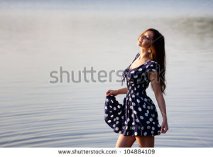 Girl in dress walking in the water - stock photo