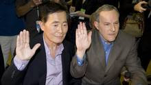 George Takei, left, and his partner Brad Altman raise their hands as ...