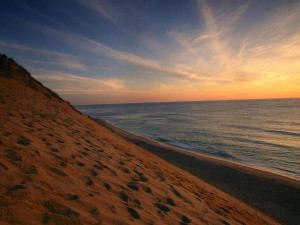 ... sunrise paints the sky pale orange over coastguard beach in cape