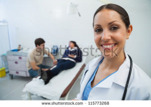 smiling in hospital room with patient in background - stock photo