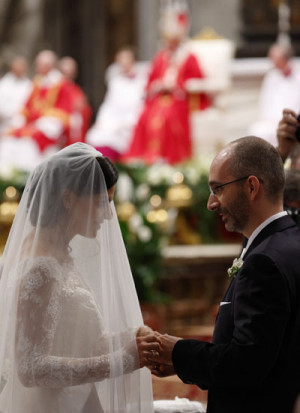 New spouses exchange rings as Pope Francis, pictured in the background ...