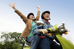 Senior couple riding motor scooter having fun.
