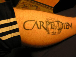 Latin quote tattoo across the forearm in bold black text.