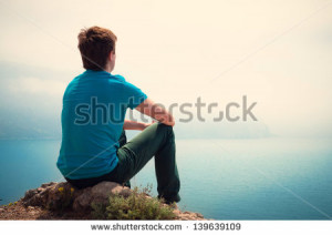 Lonely guy looking into the distance at sea - stock photo