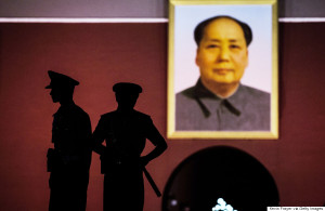 Chinese Paramilitary security force officers stand under a portrait of ...