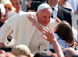 Pope Francis accepts a hug from a girl as he arrives to celebrate Mass ...