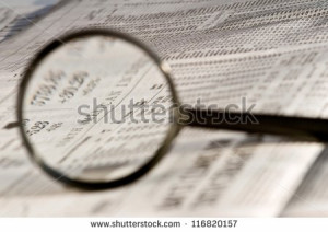 Magnifying glass highlighting investment stock quotes in newspaper ...