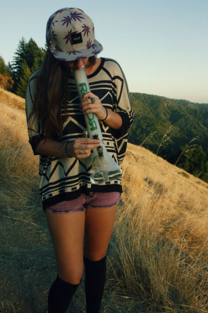 420 girl taking a big bong hit outside while walking in a field next ...