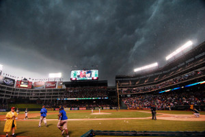 Ground crew members run to cover the field as heavy rains cause the ...