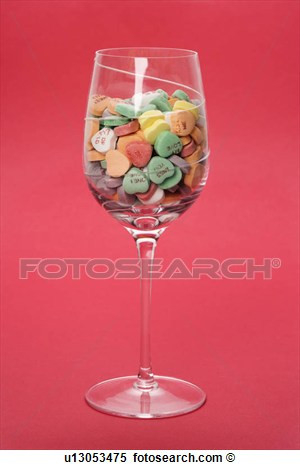 Stock Image - Wine glass full of colorful candy hearts with sayings on ...