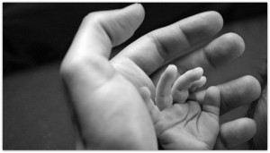 Father holding his baby hand.