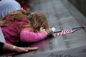 Grief: A young girl cries as she lies against the name of a loved one ...