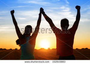 Successful couple of young athletes raising arms to golden summer ...