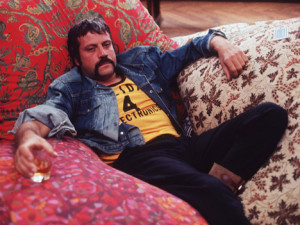 Oliver Reed, sporting a handle-bar moustache, relaxing with a drink ...