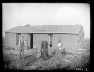 woman, a man, a child, and a man holding a newspaper stand outside a ...