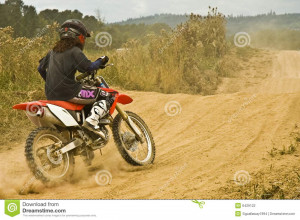 Forty plus caucasian female learning to ride dirt bike on a dusty sand ...