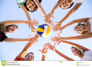 Group of young people playing volleyball on the beach.