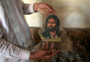 resident holds a broken picture of Imam Ali, the first Shiite Imam ...