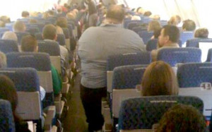 An image of an obese passenger squeezed into an economy airline seat ...
