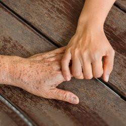 Young child's hand holding old grandparent's hand