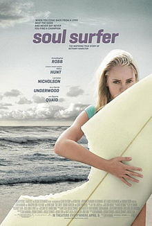young girl holds a surfboard at the beach. A section of her board is ...