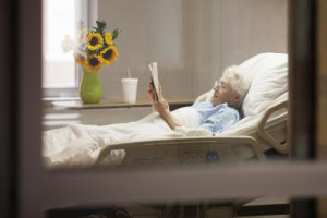 ... woman with glasses reading a book while lying in a hospital bed in