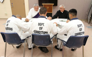 , facing forward left, and Deacon Gregory Pecore pray with inmates ...