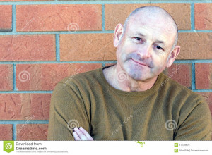 Portrait of a handsome middle aged man standing next to a brick wall ...