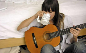 Cat Power sipping her coffee as she plays her guitar