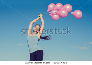 Young happy smiling woman arms raised holding pink flying balloons on ...