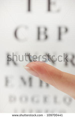 contact lens on finger, on snellen eye chart background - stock photo