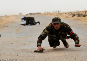 Libyan rebel fighters run for cover as shells explode nearby in the ...