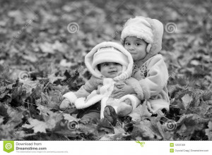 Black and white portrait of sisters cuddling in pile of fallen autumn ...