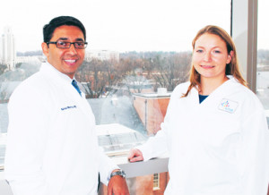 man and woman in white coats with window in background overlooking NIH