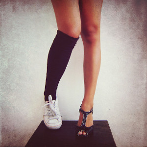 Close-up of a woman's legs and feet. On her right foot is a sneaker ...