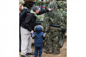 father and son take a look at a British Army sniper in his full ...