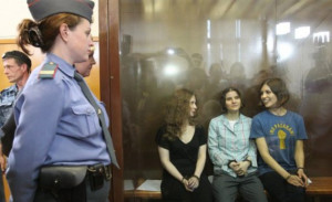 ... Riot sit in a glass-walled cage after being sentenced in Moscow. AFP
