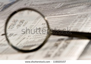 ... glass highlighting investment stock quotes in newspaper - stock photo