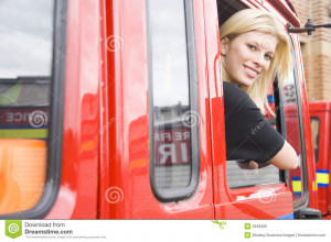 Female firefighter sitting in the cab of a fire engine.