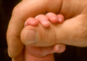 baby hand holding father's thumb
