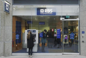 woman stands in front of a Royal Bank of Scotland (RBS) cash machine ...