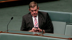Peter Slipper checks his messages on the House of Representatives back
